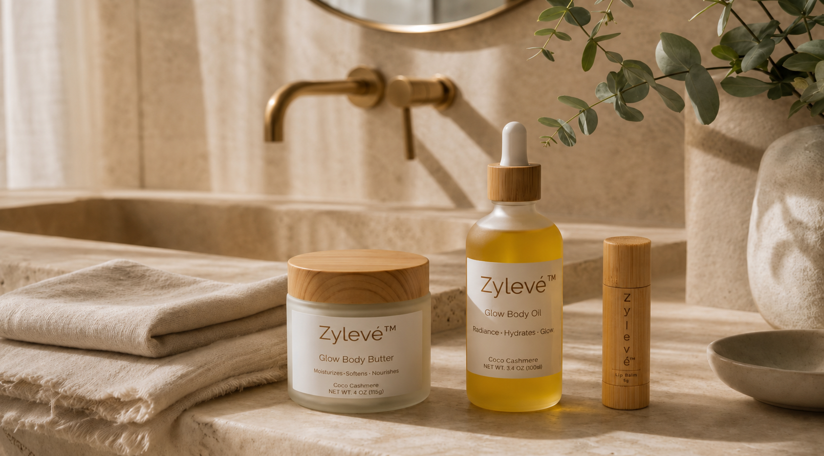 Zylevé Glow Body Butter, Glow Body Oil and Lip Balm arranged in a warm marble bathroom